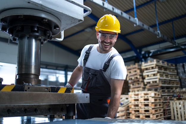 Portrait of factory worker with arms crossed standing by drilling machine in industrial plant