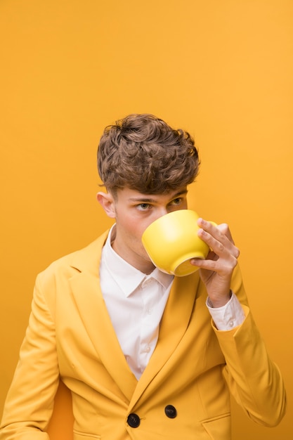 Free photo portrait of fashionable boy drinking from a cup