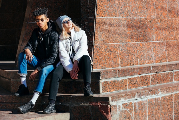 Portrait of fashionable interracial young couple sitting outdoor