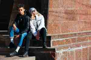 Free photo portrait of fashionable interracial young couple sitting outdoor