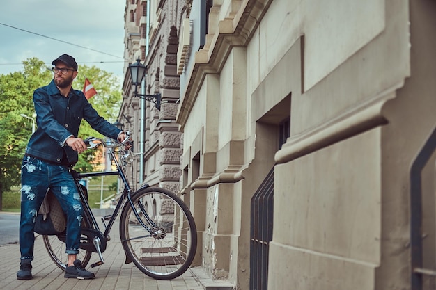 Portrait of a fashionable man in stylish clothes walking with city bicycle on the street.