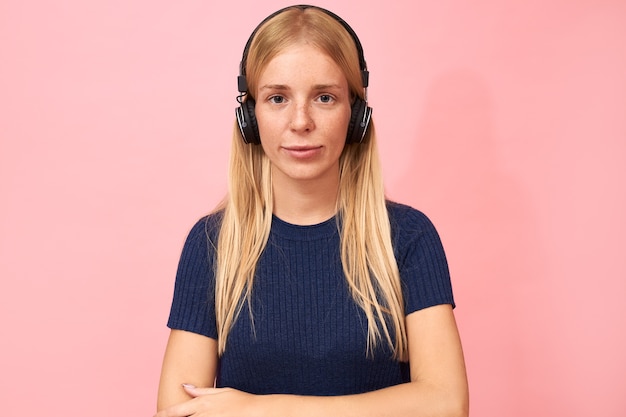 Free Photo portrait of fashionable student girl with nose ring posing on pink in wireless headphones, listening to online lecture, audio book or podcast