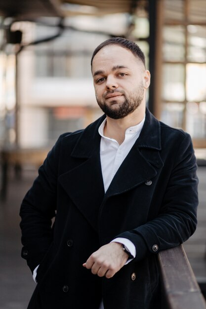 Portrait of fashionable well dressed man with beard posing outdoors