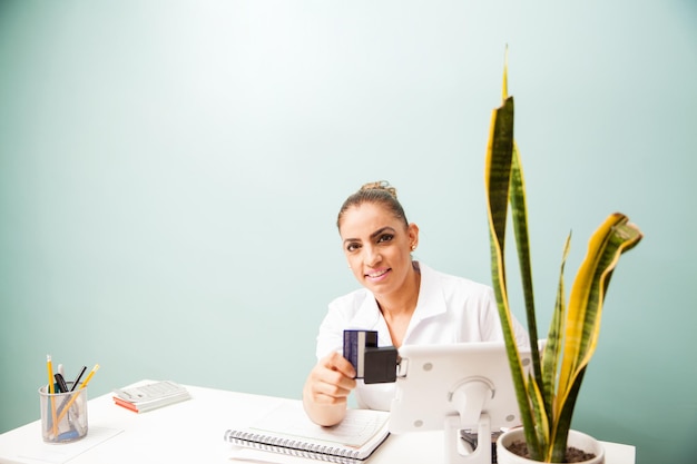 Portrait of a female cashier at a business front desk swiping a credit card in a reader and smiling