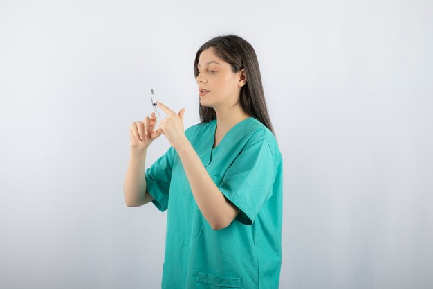 Portrait of female doctor holding a large syringe. 