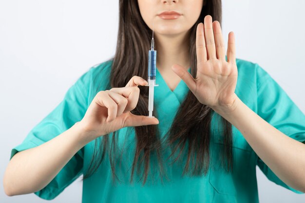 Portrait of female doctor holding a large syringe.