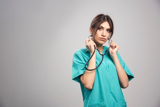 Portrait of female doctor posing with stethoscope on gray