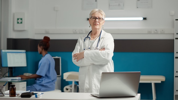 Free photo portrait of female doctor with medical expertise feeling confident about health care system in cabinet. physician waiting to start checkup visit and consultation appointments with patient.