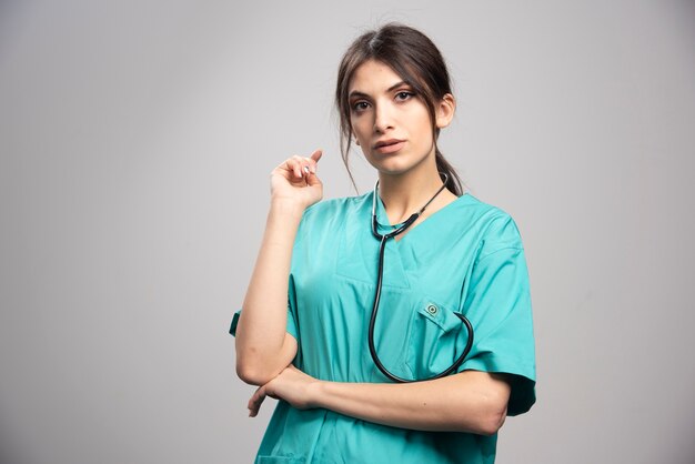 Portrait of female doctor with stethoscope on gray