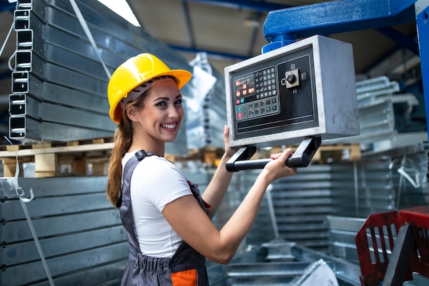 Portrait of female factory worker operating industrial machine and setting parameters on the computer