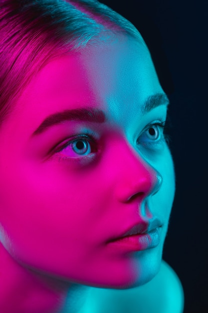 Free photo portrait of female fashion model in neon light on dark studio