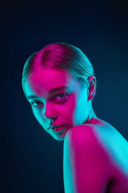 Portrait of female fashion model in neon light on dark studio