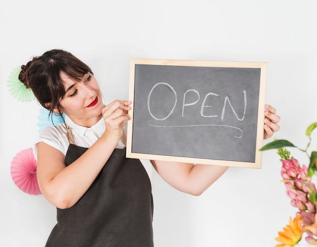 Free photo portrait of a female florist with slate showing open word