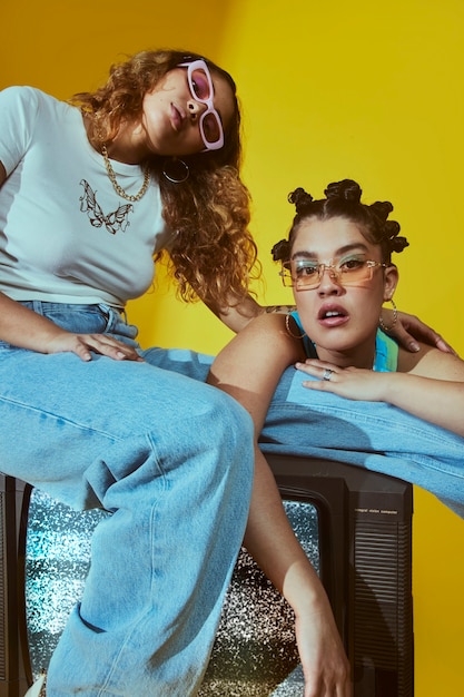 Portrait of female friends in 2000s fashion style posing together with tv