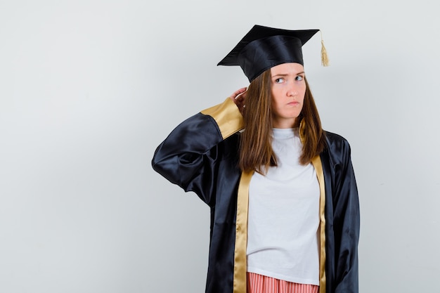 Free photo portrait of female graduate holding hand behind head in uniform, casual clothes and looking pensive front view