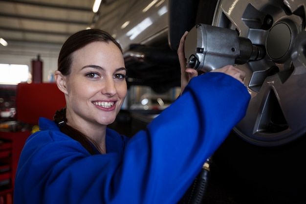 Portrait of female mechanic fixing a car wheel