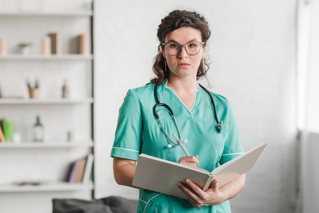 Free photo portrait of female nurse holding book and pen