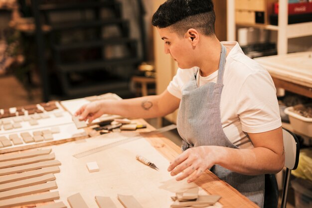 Portrait of a female potter arranging the clay tiles on the wooden table in the workshop