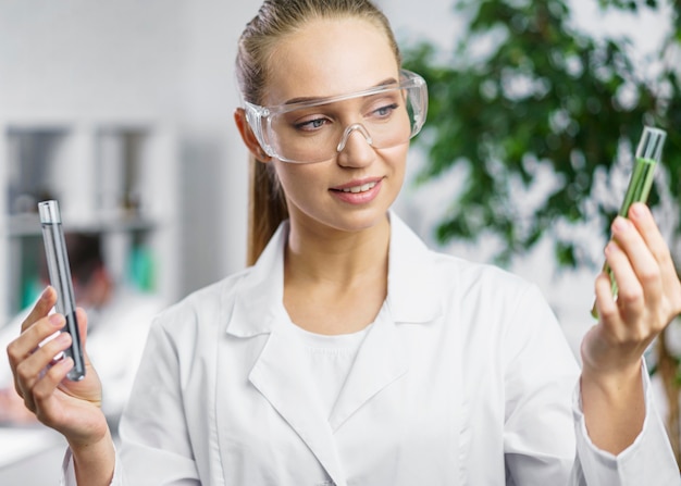 Free photo portrait of female researcher in the lab with test tubes and safety glasses