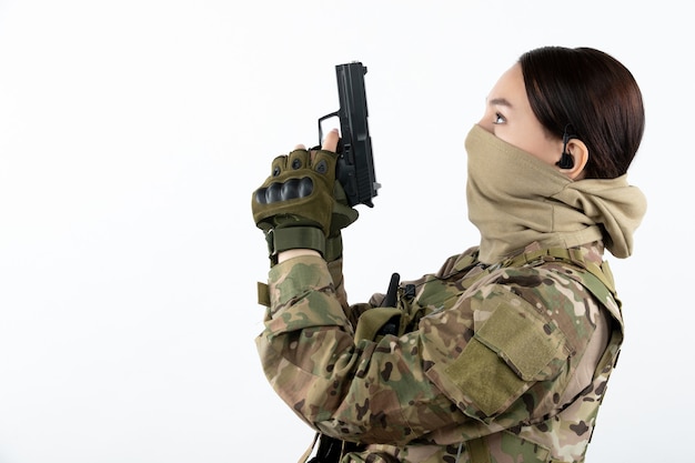 Free Photo portrait of female soldier with gun in camouflage white wall