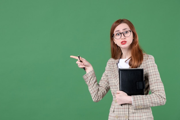 Free photo portrait of female teacher with notepad on green