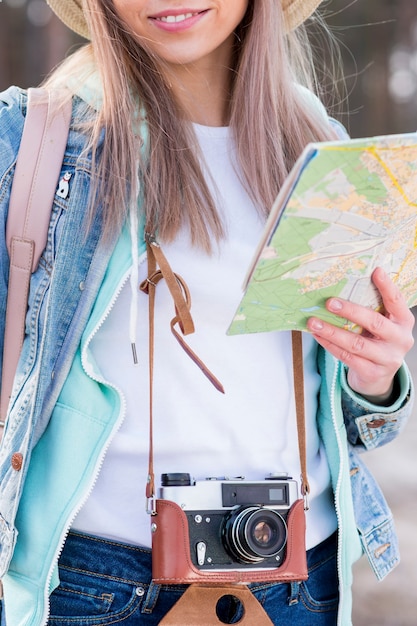 Free Photo portrait of a female traveler holding vintage camera and map