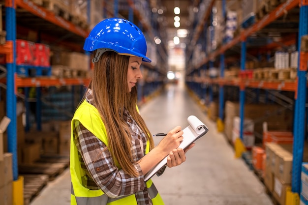 Portrait of female worker in distribution warehouse taking notes