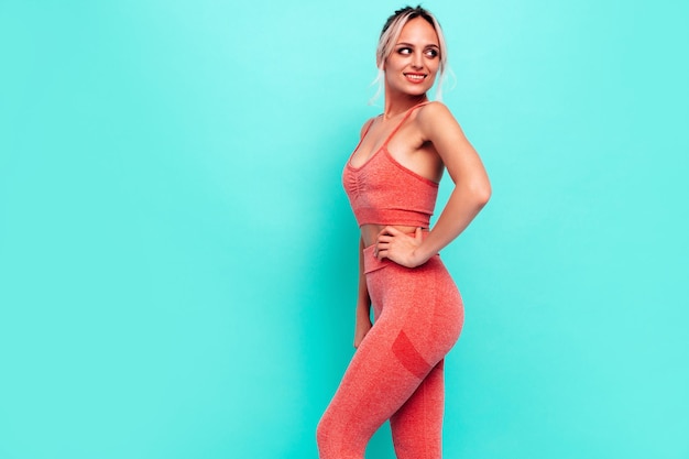 Free photo portrait of fitness woman in pink sports clothing young beautiful model with perfect bodyfemale posing near wall in studiocheerful and happy stretching out before training