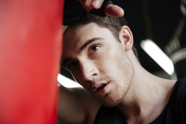 Portrait of focused young boxer looking away near punching bag