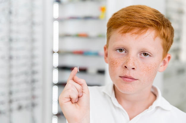 Portrait of freckle boy with contact lens at optics clinic