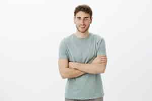 Free photo portrait of friendly joyful male coworker in casual outfit standing with crossed arms and smiling with friendly happy expression while waiting for wife to get dressed for walk