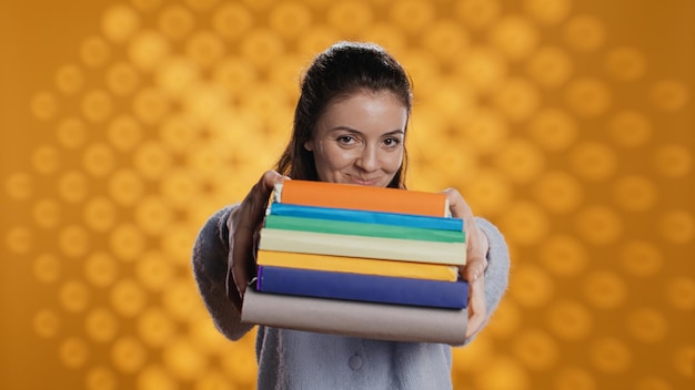 Free photo portrait of friendly woman offering stack of textbooks useful for school