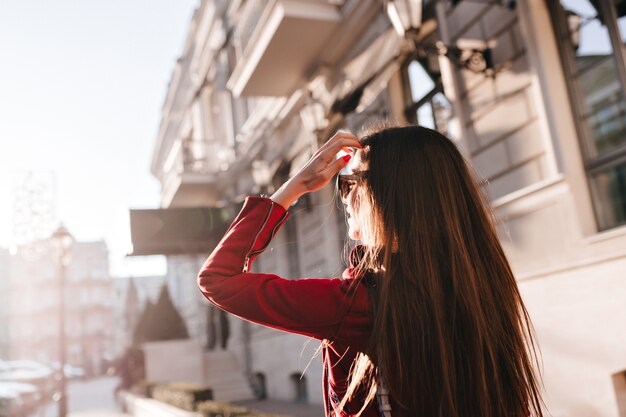 Portrait from back of long-haired girl walking around city in sunny day