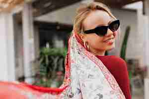 Free photo portrait from back of smiling woman wearing black sunglasses and shawl in the head