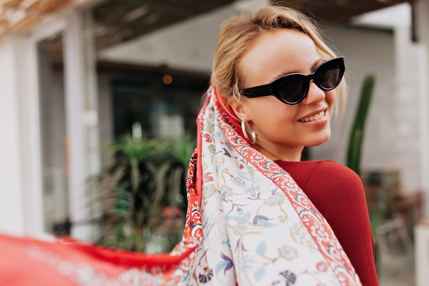 Free Photo portrait from back of smiling woman wearing black sunglasses and shawl in the head