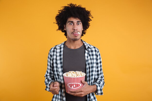 Portrait of a funny afro american man eating popcorn