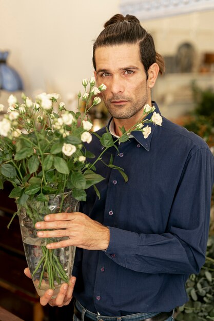 Portrait of gardener man with long hair holding flowers