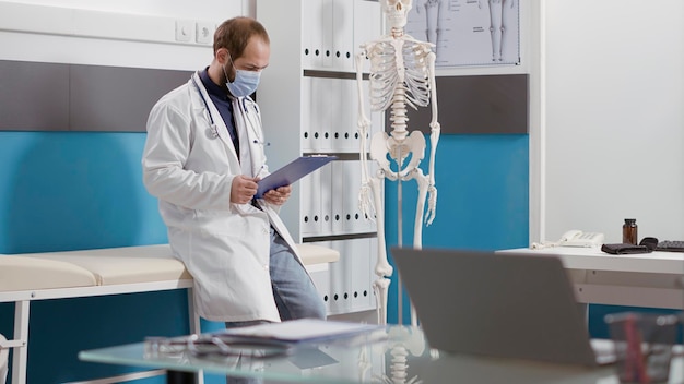 Free photo portrait of general practitioner with white coat and stethoscope smiling in front of camera. male physician having medical expertise and preparing for health care checkup appointment.