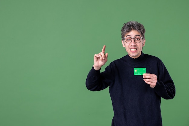 Portrait of genius man holding credit card in studio shot green wall