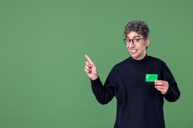 Portrait of genius man holding green credit card in studio shot green wall