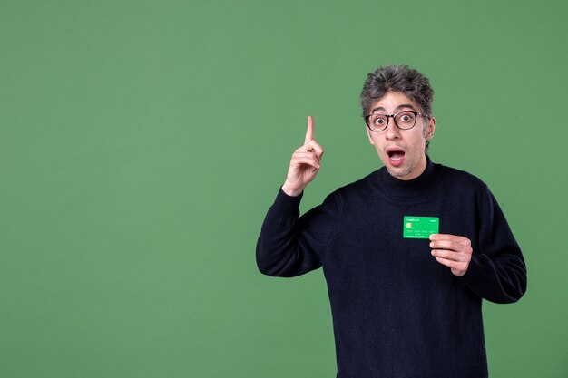 Portrait of genius man holding green credit card in studio shot green wall