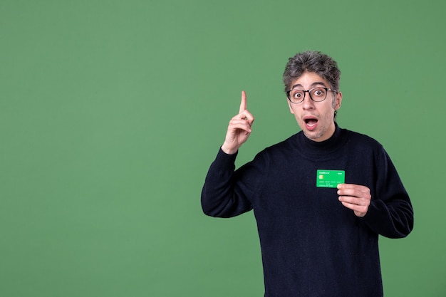 Portrait of genius man holding green credit card in studio shot green wall