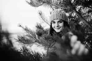 Free photo portrait of gentle girl in gray coat and hat against new year tree outdoor