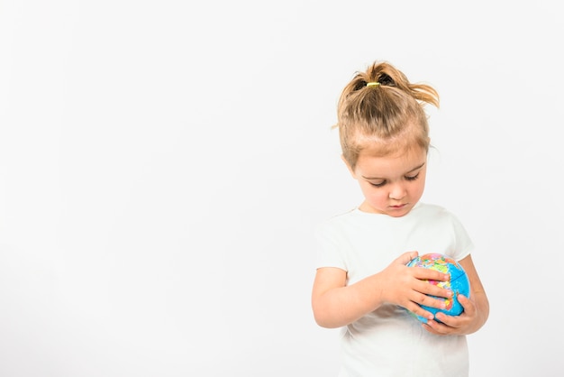 Portrait of a girl holding globe ball against white background