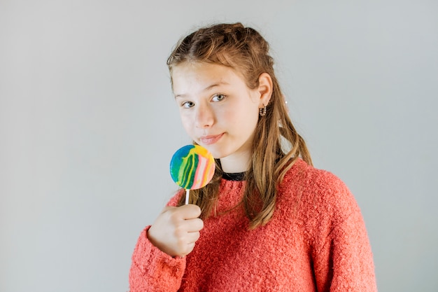 Portrait of a girl holding lollipop on grey background