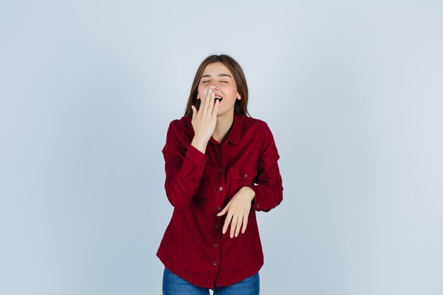 Portrait of girl keeping hand on mouth in casual shirt and looking happy