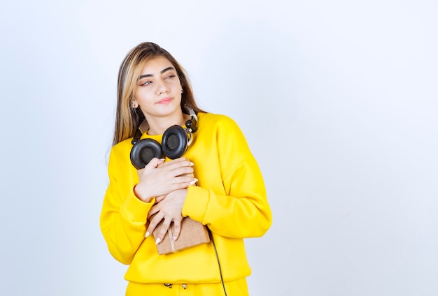 Portrait of a girl model holding a paper box with bow isolated over white wall