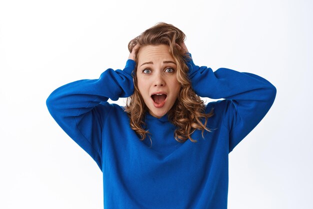 Free Photo portrait of girl in shock panicking holding hands on head and looking troubled and alarmed white background