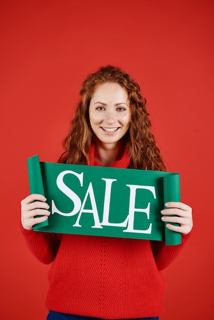 Free photo portrait of girl showing banner of winter sale