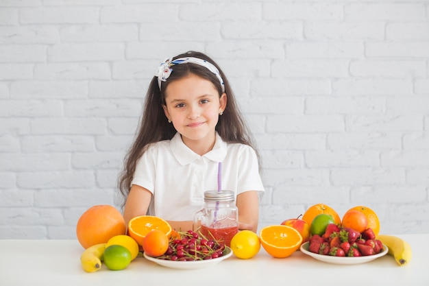 Free photo portrait of a girl with colorful ripe fruits on the desk